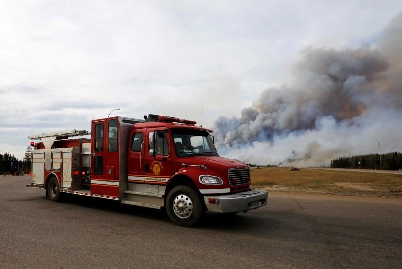 A fire truck drives by the wildfires near Fort McMurray, Alberta, Canada, May 7, 2016. REUTERS/Mark Blinch