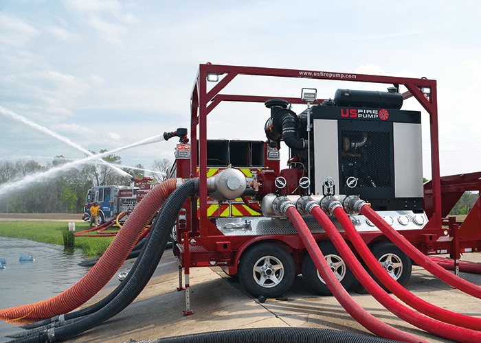 A US Fire Pump 5,500 GPM Mobile Trailer Unit supporting an industrial pumper.