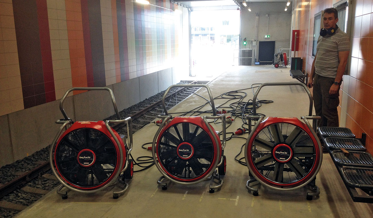 Three fans on the platform aimed towards the staircase. In the back, the inlet opening can be seen.
