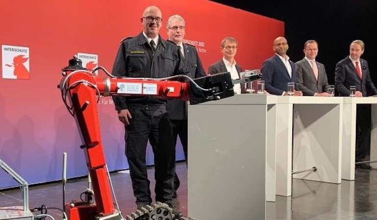 (from left to right): D2 Roboter, Dirk Aschenbrenner, President of the Association for the Promotion of German Fire Protection (vdfb); Karl-Heinz Banse, President of the German Fire Brigades Association (DFV); Dr. Bernd Scherer, Managing Director of VDMA Fire Fighting Technology; Onuora Ogbukagu, Corporate Spokesperson Deutsche Messe; Dr. Jochen Köckler, Chairman and CEO Deutsche Messe and Bernd Heinold, Senior Project Manager INTERSCHUTZ at Deutsche Messe. (INTERSCHUTZ)
